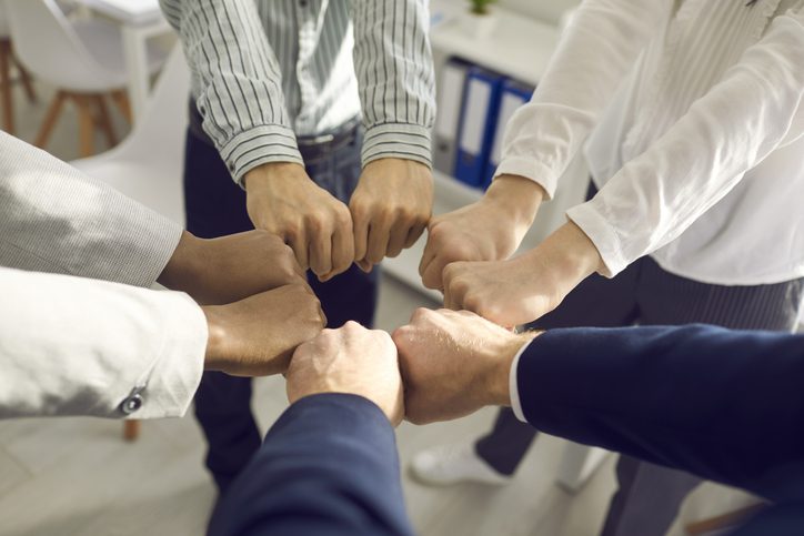 Teamwork, teambuilding, responsibility and equal opportunities. Close up top view of interracial business people team or diverse student hand holding together bumping fists in circle as unity symbol